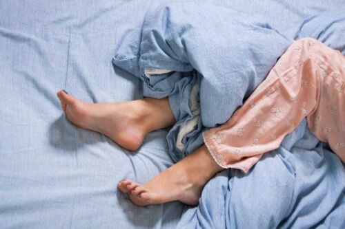 Bare feet of a young woman on blue bed