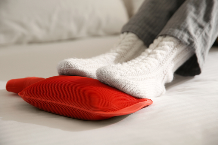 Person warming feet with hot water bottle
